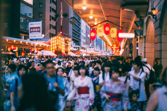 手前の人混みをボカして山鉾や提灯の明かりを引き立てる